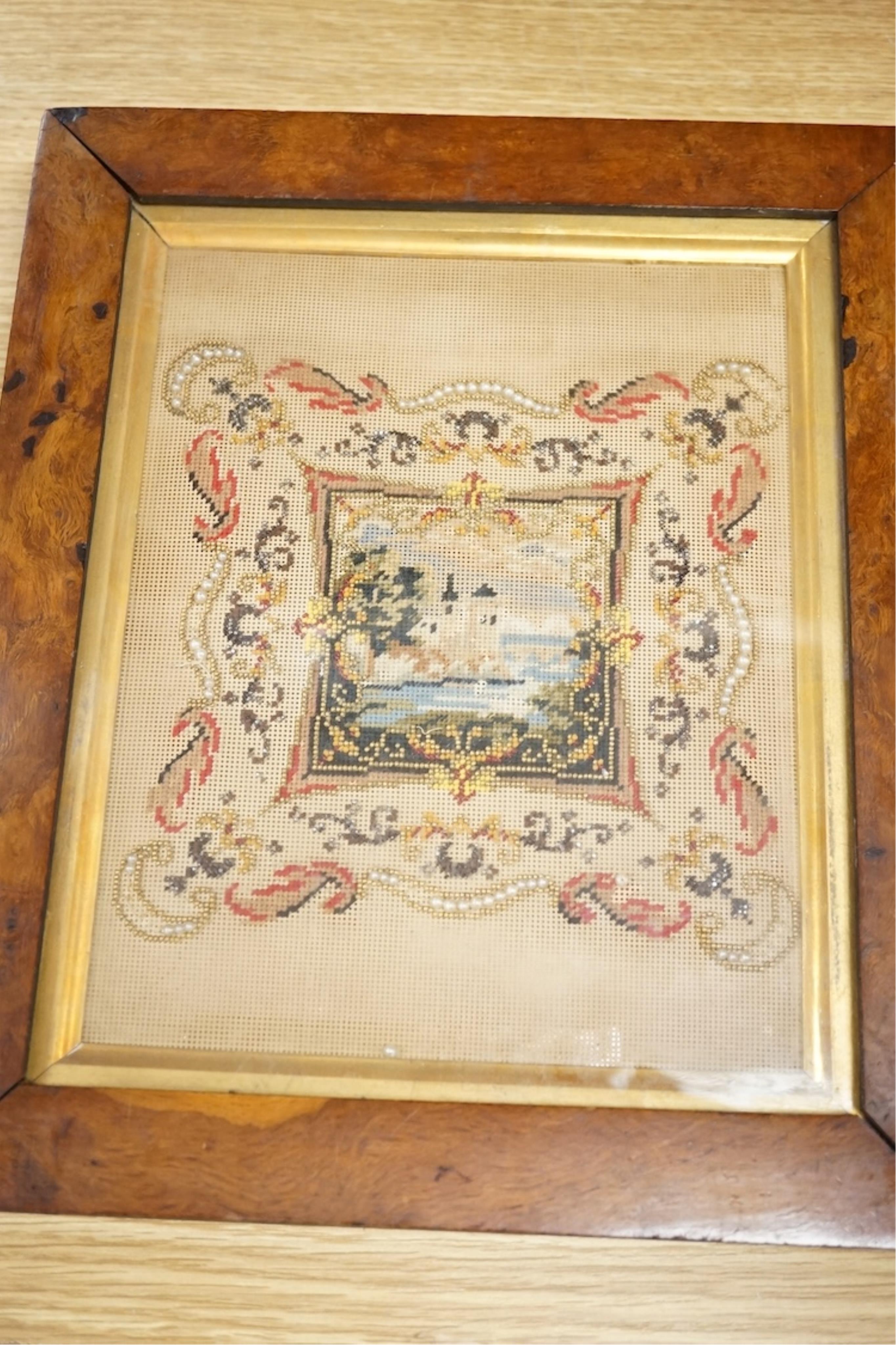 A framed 19th century Berlin bead worked embroidery, worked as a small cartouche of a moated castle with a decorative border, overall 30cm high
